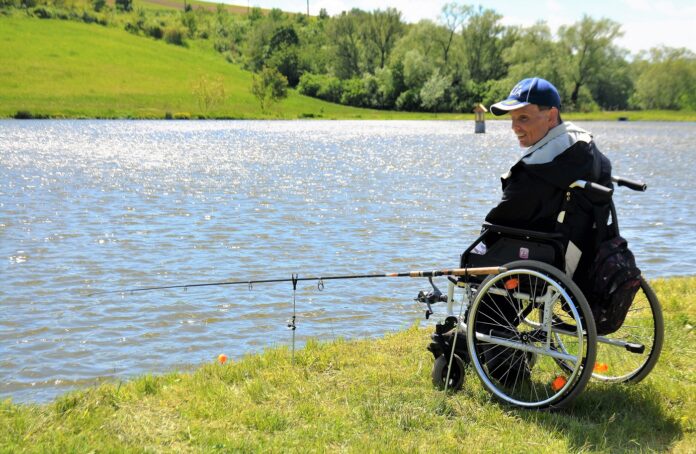 Handicapovaný rybář na invalidním vozíku rybaří na rybníku