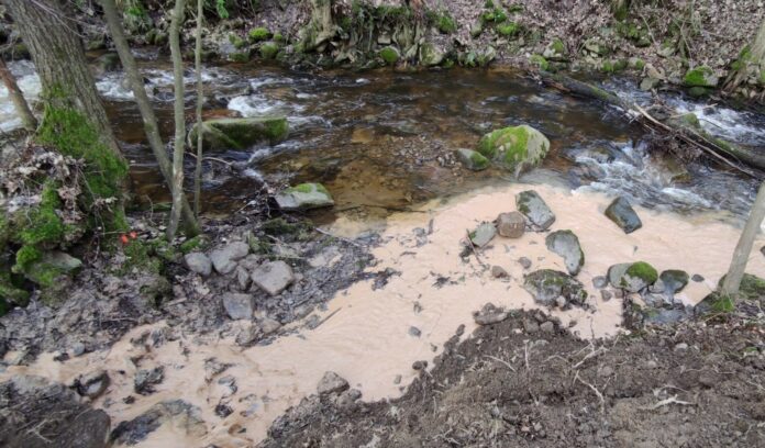 Lobezský potok plný znečištěné vody, která vytéká z lomu