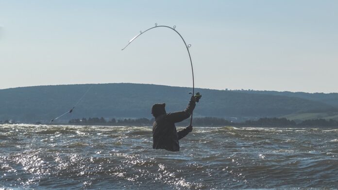 Rybář nahazuje montáž do velké vzdálenosti ve velkých vlnách