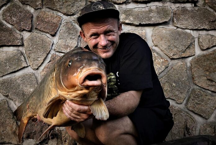 Rybář Tomáš Blažek ukazuje uloveného kapra