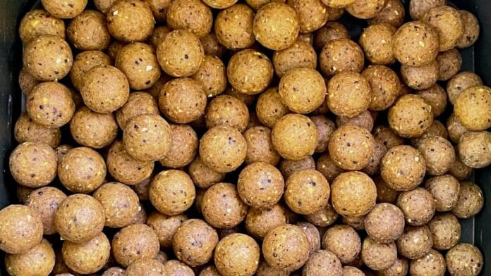 Tray of brown energy bites with small white sesame seeds visible on the surface