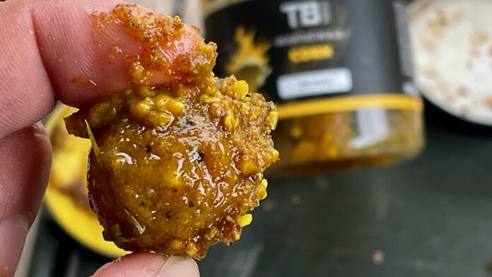 Close-up of a crispy honey-glazed chicken nugget with crumb coating held by fingers.