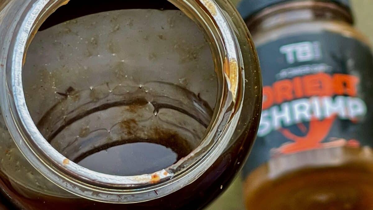 Close-up of an open jar with dark, muddy liquid and rust around the rim.