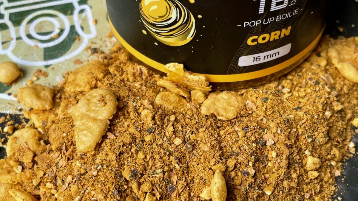 Close-up of a black-and-yellow container lying on its side with crushed cornmeal and puffed corn pieces scattered around.