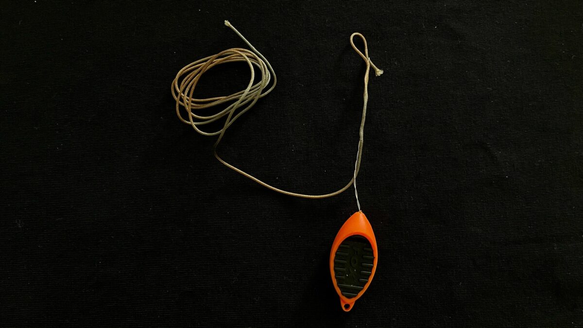 Orange handheld retractable tape measure with a black grip, connected to a long, twisted metal tape on a dark background.
