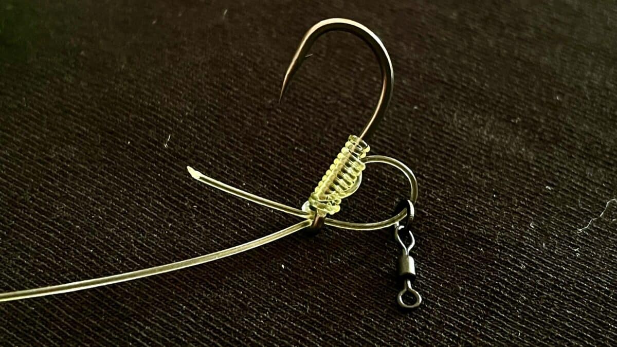 Close-up of a metal hoop earring with a coiled spiral bead detail on a dark textured surface.