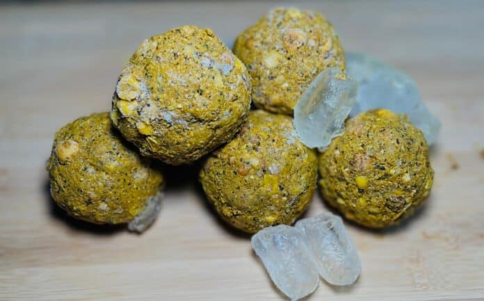 Nut-coated energy bites clustered on a wooden surface with a few ice cubes nearby
