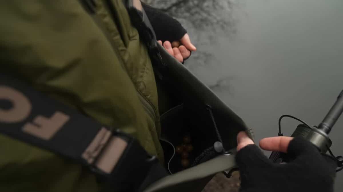 Close-up of gloved hands handling outdoor gear and a black device with a cable nearby.