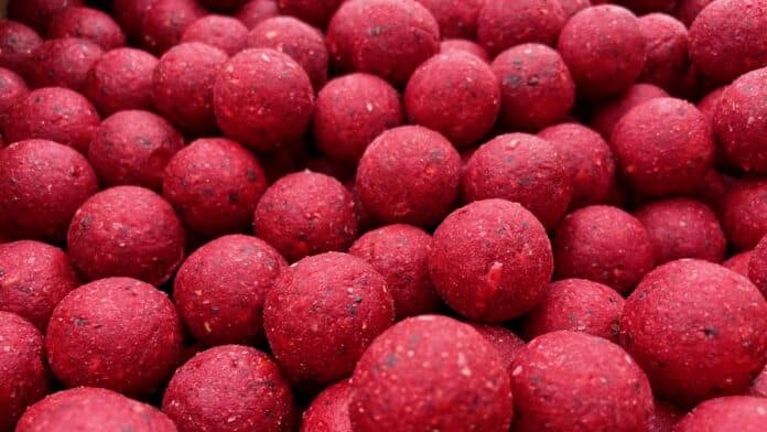 Close-up of many red, textured spherical candies packed together.