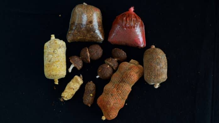 Assorted cured sausages in mesh bags arranged on a dark surface.
