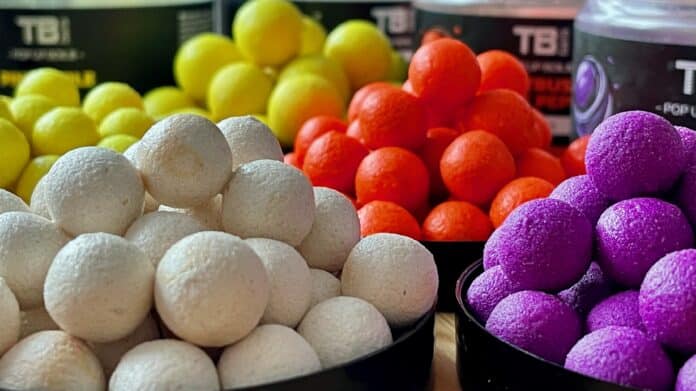 Assorted colorful bath bombs arranged in bowls: white, yellow, orange, purple spheres stacked in a display.