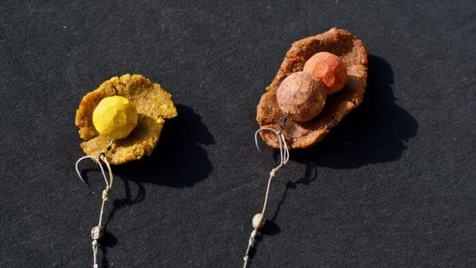 Handmade clay bead earrings on dark fabric, yellow piece on left and brown-red piece on right with string dangles