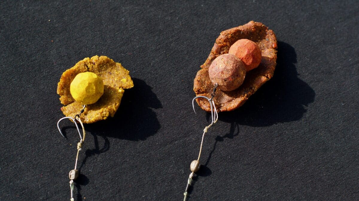 Two rustic pendant-like jewelry pieces on black fabric: each features a colored spherical bead resting on a rough stone base, hung by cords with small beads at the ends (displayed).