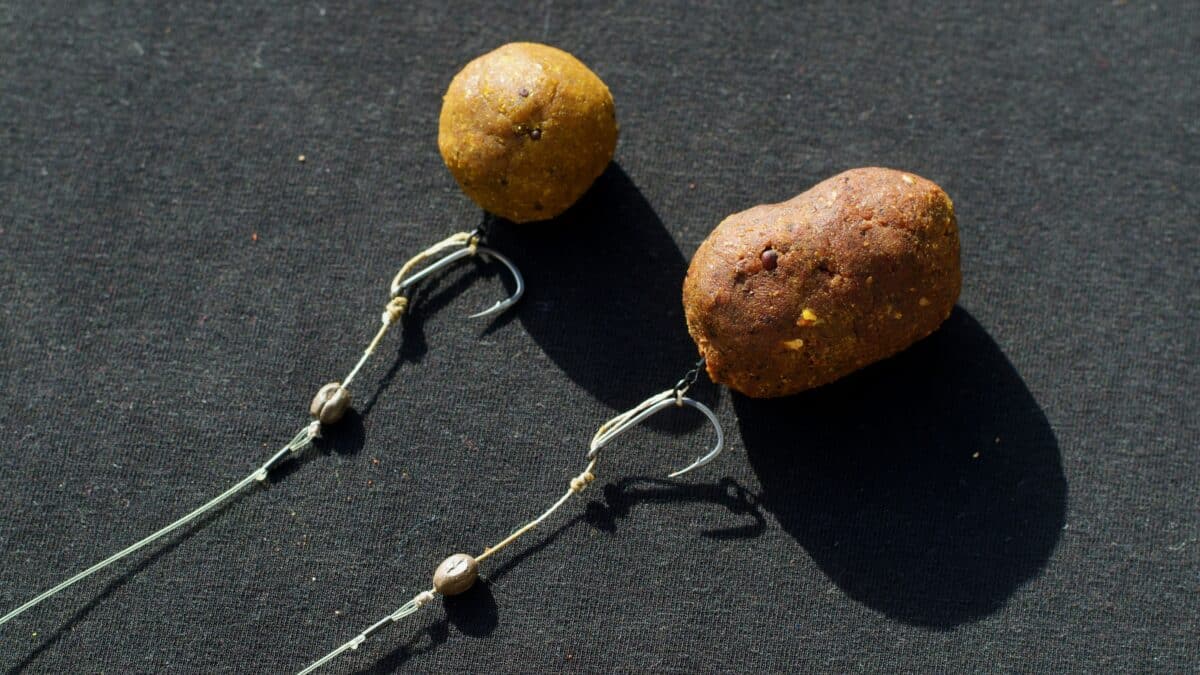 Two brown textured beads tied to curved metal wires on a dark fabric background, part of handmade jewelry.