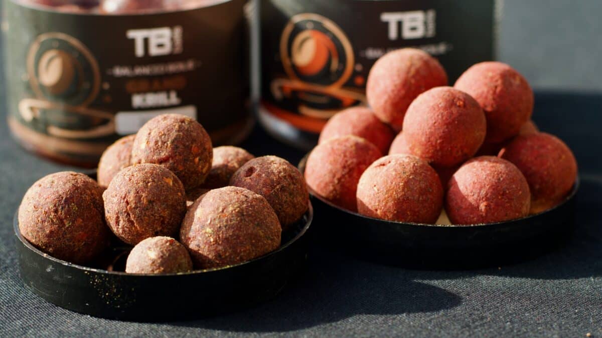 Close-up of pink-red coated energy balls on a dark tray, with blurred snack jars in the background.