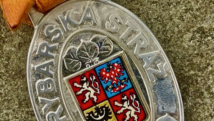 Close-up of a silver medal with a four-quadrant coat of arms and a blue-red shield, surrounded by raised text along the rim